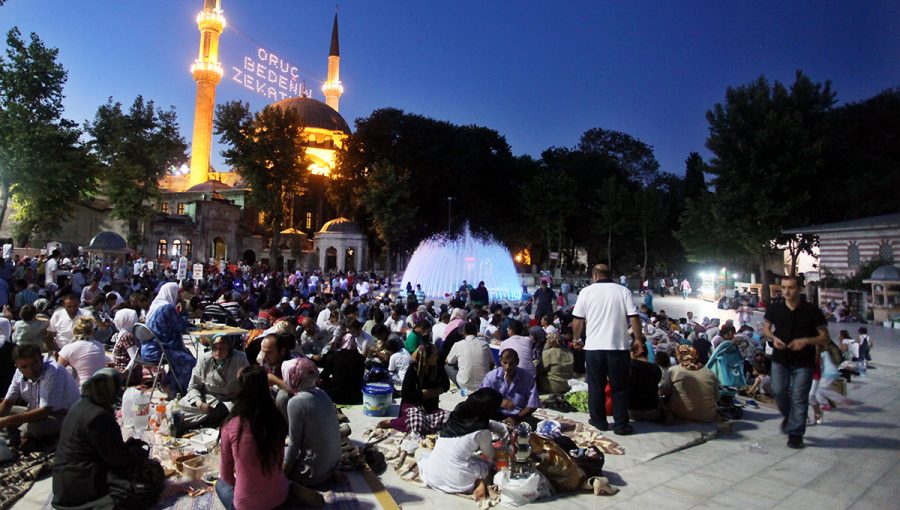 Istanbul, Turecko - 8.August 2011: Ľudia sediaci na zemi a jediaci na sviatok ramadánu pod svietiacimi vežami mešity. Zdroj: iStockphoto.com