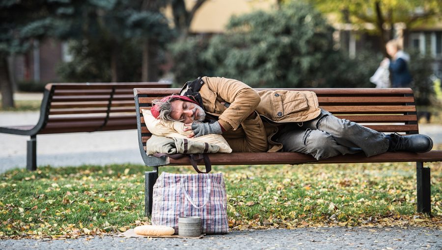 Bezdomovec spiaci na lavičke. Zdroj: iStockphoto.com