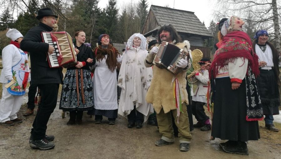 Fašiangový sprievod v Múzeu slovenskej dediny (ľudia (zhruba 10)v kostýmoch a maskách spievajú a dvaja z nich hrajú na akordeónoch. Zdroj: Múzeum slovenskej dediny SNM v Martine
