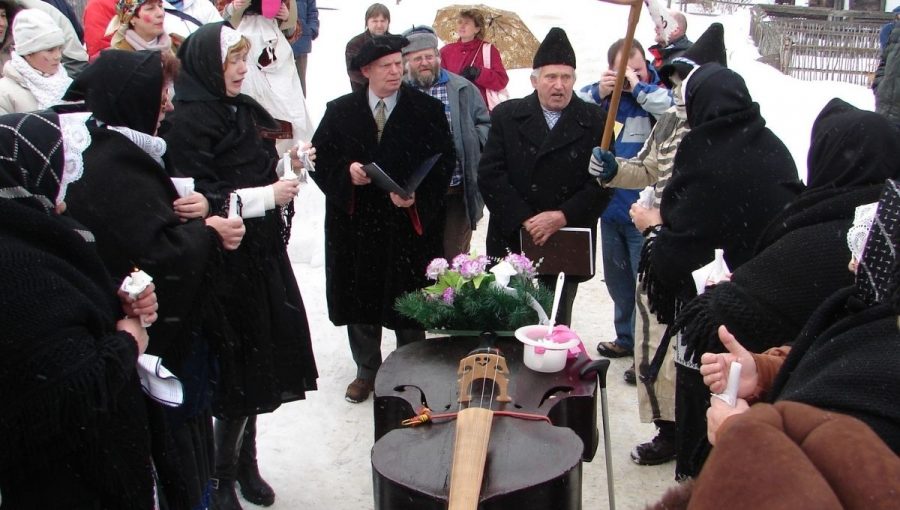 Pochovávanie basy s folklórnou skupinou z Bystričky (ľudia v čiernom ľudovom odeve okolo basy ozdobenej pohrebným vencom. Zdroj: Múzeum ľudovej kultúry SNM v Martine