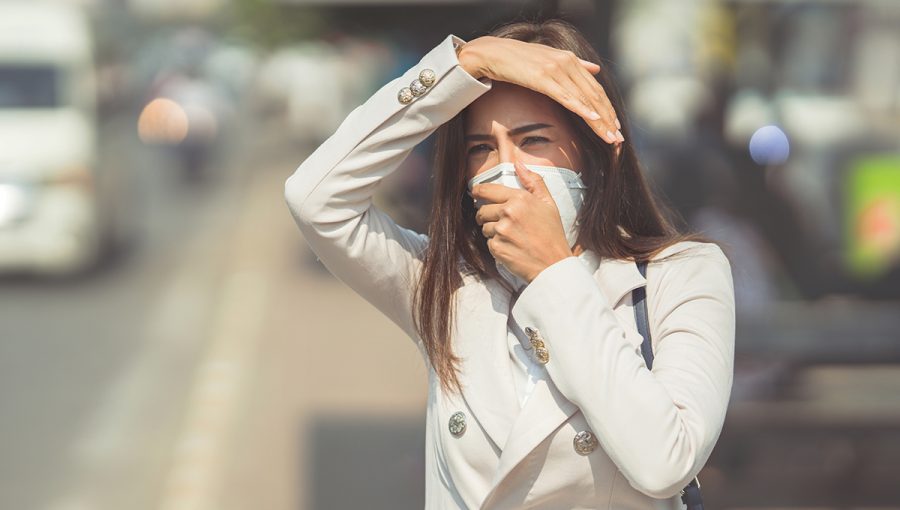 Žena idúca cez mesto s respirátorom proti smogu. Zdroj: iStockphoto.com