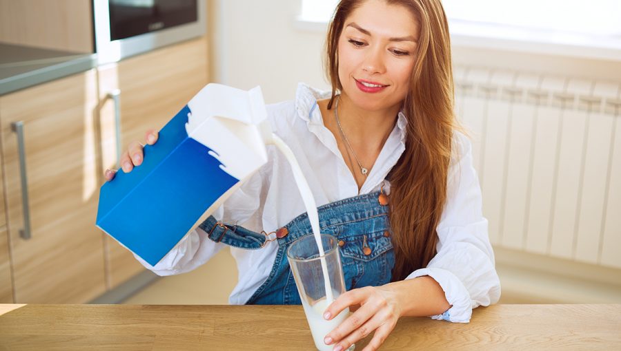 Žena nalieva mlieko z kartónovej krabice do pohára. Zdroj: iStockphoto.com