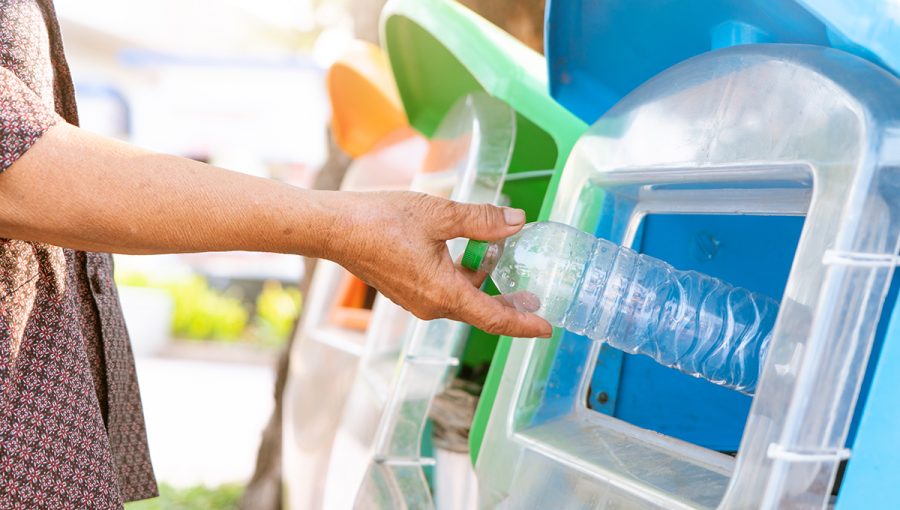 Žena vyhadzuje plastovú fľašu do kontajnera na plast. Zdroj: iStockphoto.com