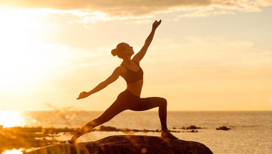 Žena na pláži cvičí yogu pri západe slnka. Zdroj: iStockphoto.com