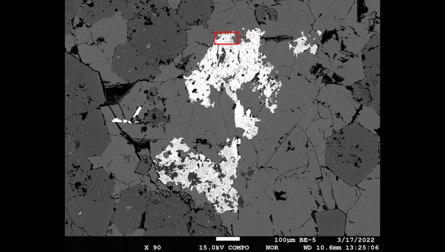 Ferriandrosit-(Ce) v spätne rozptýlených elektrónoch (svetlé zrná sú vrastené v agregáte pyroxmangitu a spessartínu). Červený obdĺžnik ohraničuje miesto, kde mineralógovia z Pisy extrahovali fragment na monokryštálovú difrakčnú analýzu. Foto: Tomáš Mikuš