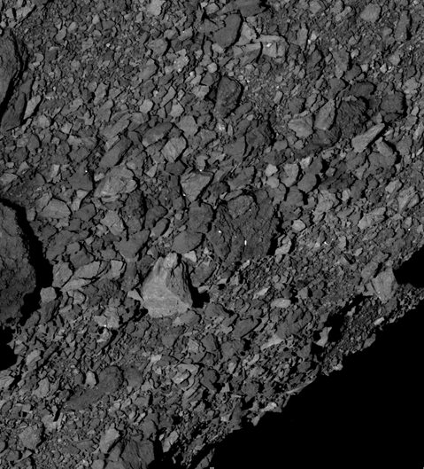 (6) Južná polguľa asteroidu Bennu pokrytá obrovským počtom balvanov rôznej veľkosti. Obraz získala 7. marca 2019 sonda OSIRIS-REx zo vzdialenosti 5 km. Veľký svetlý balvan tesne pod stredom obrazu je široký asi 7,4 metra.
