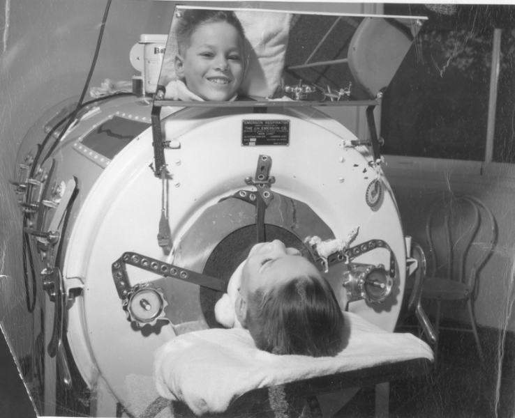 Chlapec s detskou obrnou v Emersonovom respirátore (železné pľúca), ktorý si v zrkadle prístroja prezerá fotografa (Joe Clark). Nemocnica Hermana Kiefera, Detroit,