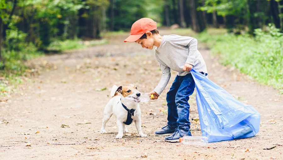 Chlapec zbiera so psom plastový odpad v prírode. Zdroj: iStockphoto.com