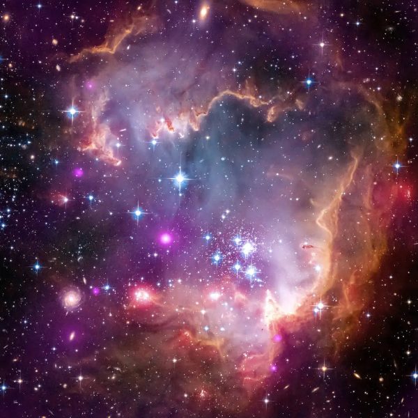 Na zloženej snímke je oblasť tvorby hviezd v neďalekej galaxii Malý Magellanov mrak. Začiatkom roka 2024 vedci oznámili, že za sebou zrejme ukrýva ďalšiu galaxiu. Zdroj: NASA