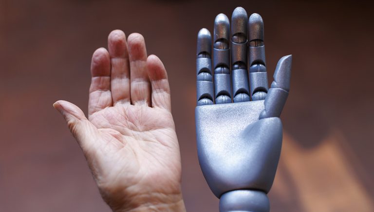 Ľudská a robotická ruka. Zdroj: iStock.com/aerogondo