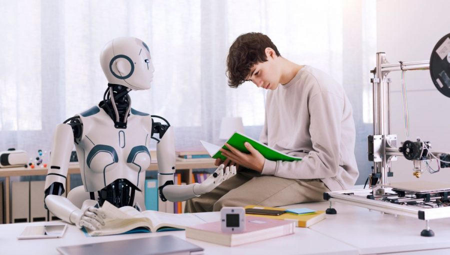 Robot sediaci za stolom a chlapec čítajúci knihu.