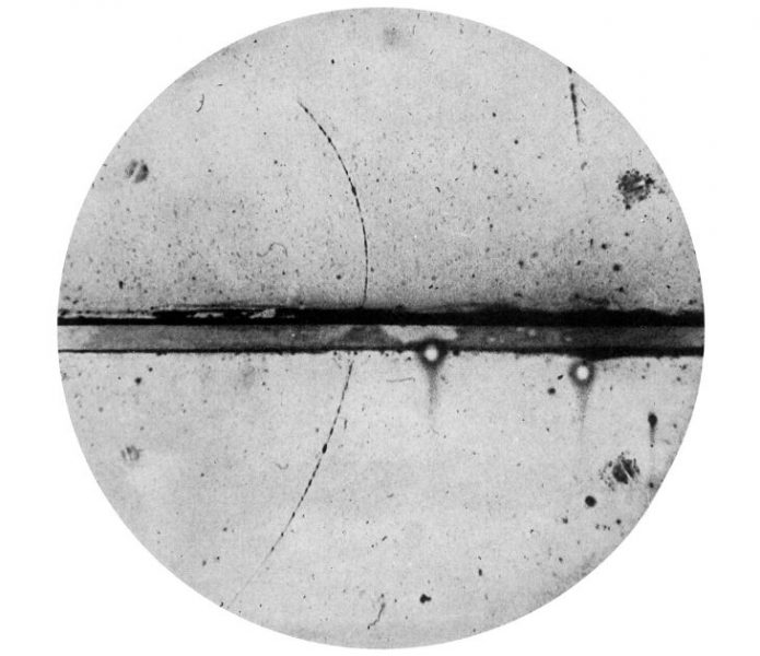 Fotografia hmlovej komory C. D. Andersona, prvého identifikovaného pozitrónu. Hornú a dolnú polovicu komory Anderson oddelil 6 mm olovenou doskou. Pozitrón musel prísť zdola, keďže horná stopa v magnetickom poli je viac ohnutá, indikujúc nižšiu energiu.