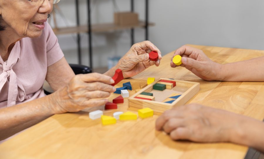 Staršia žena ukladá kocky. 