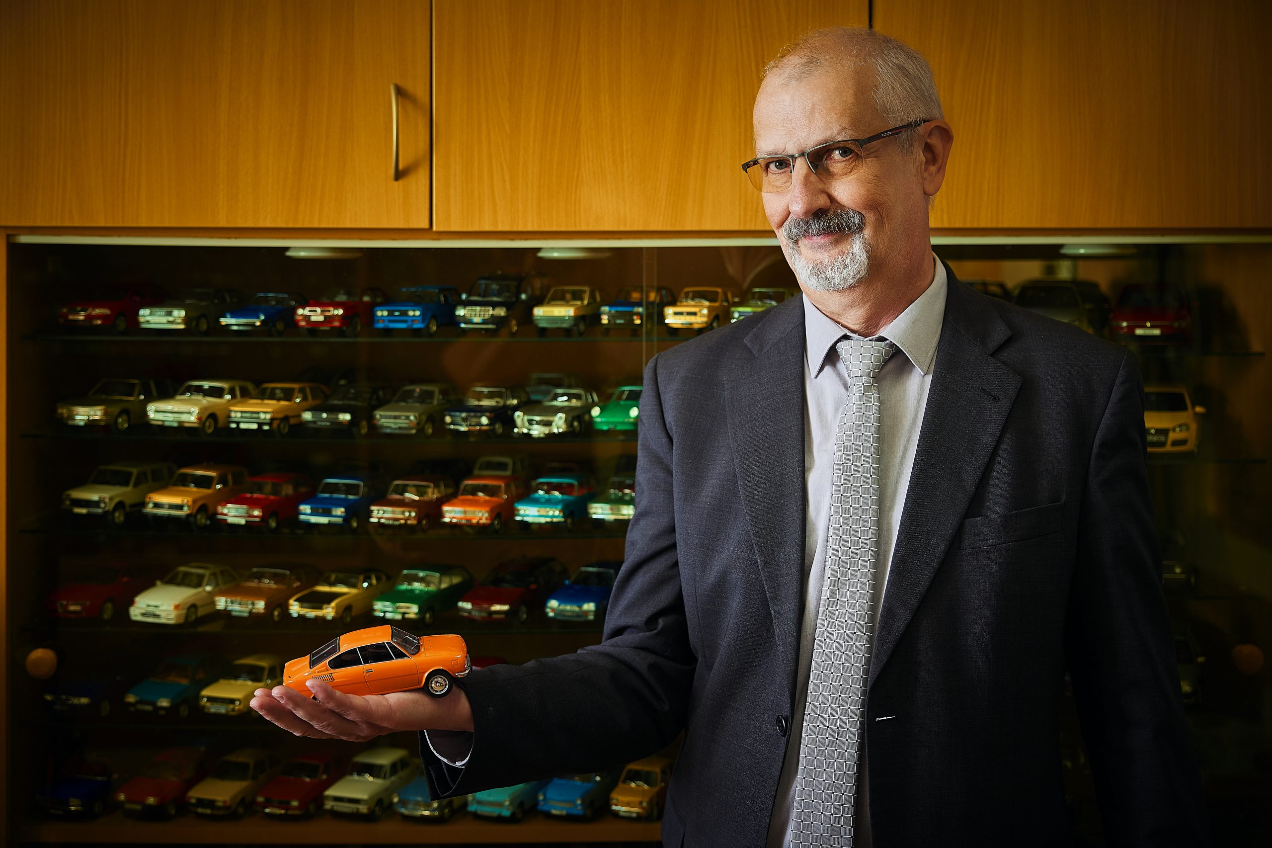 Muž drží v ruke auto. 