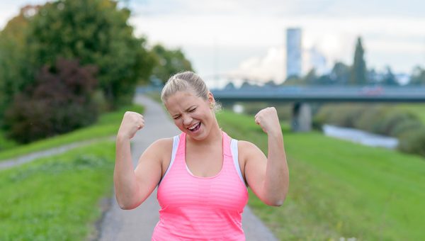 Ilustračné foto: Bežiaca žena s nadváhou s víťazným gestom. Zdroj: iStock