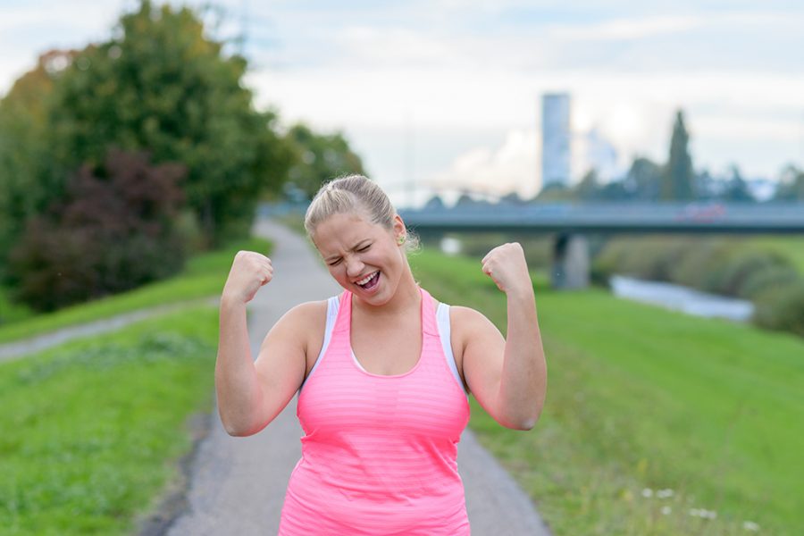 Ilustračné foto: Bežiaca žena s nadváhou s víťazným gestom. Zdroj: iStock