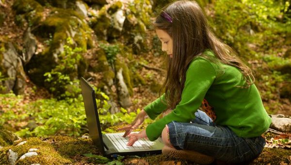 Ilustračné foto: Dievčatko s notebookom v lese. Zdroj: iStock