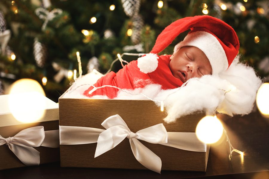 Ilustračný obrázok: bábätko oblečené ako Santa Claus spí v ozdobenej škatuli. Zdroj: iStock