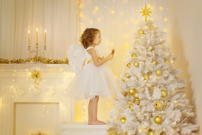 Ilustračný obrázok: biely plastový vianočný stromček a dievčatko, ktoré ho zdobí. Zdroj: iStockphoto.com