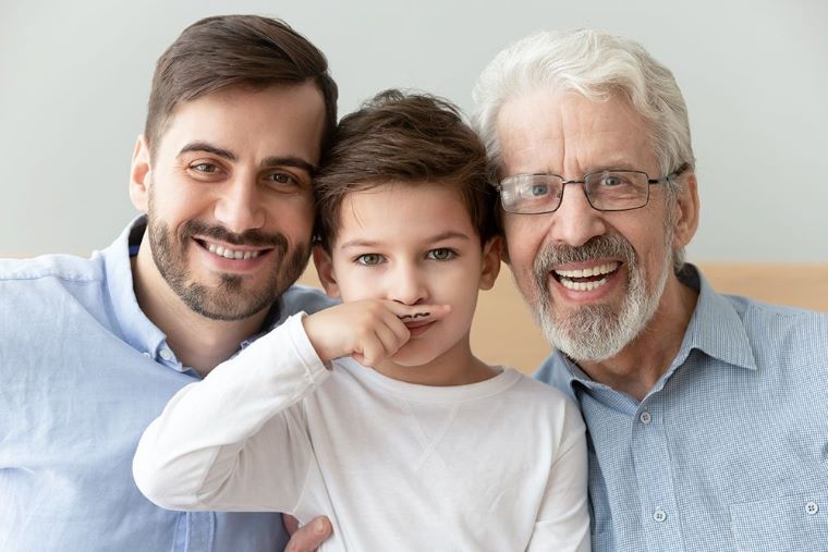 Ilustračný obrázok: Otec, syn, praotec. Syn - dieťa, si pridŕža nakreslené fúzy. Zdroj: iStock