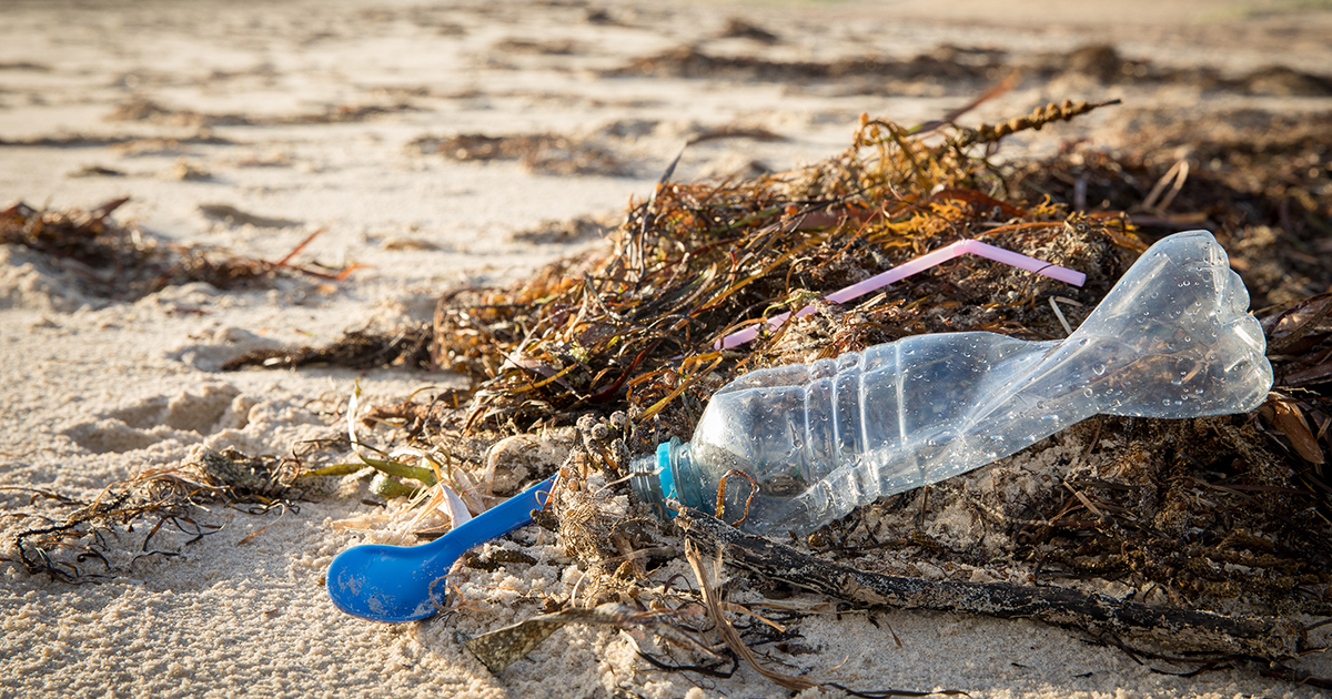 Ilustračné foto: breh mora, plastový odpad — lyžička, slamka a fľaša. Zdroj: iStockphoto.com